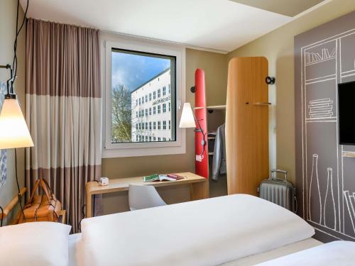a bedroom with a bed and a desk and a window at ibis Landshut City in Landshut