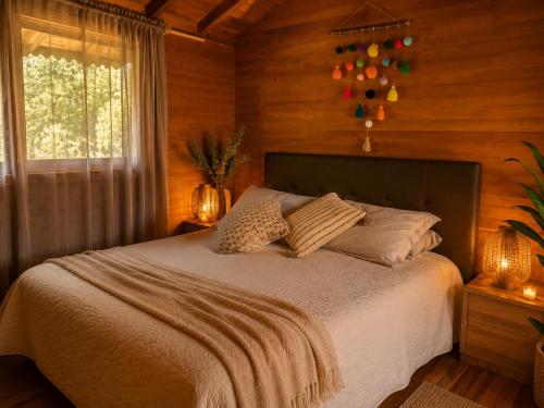a bedroom with a bed with wooden walls and a window at Beehouse Arví Cabaña in Guarne