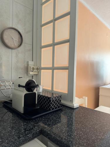 a kitchen counter with a toaster and a clock on the wall at Ofir Guest House in Fão