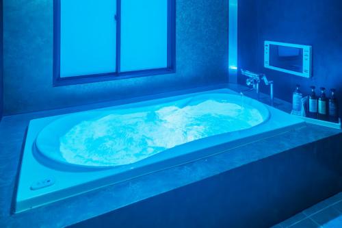 a bathroom with a tub with blue lighting at HOTEL Lien in Ashiya