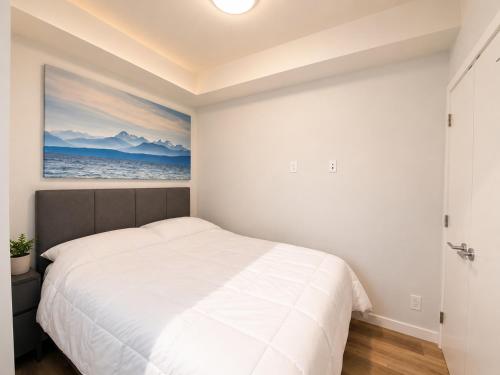 a bedroom with a white bed and a painting on the wall at Perfect Brand New Condo Downtown Sidney in Sidney