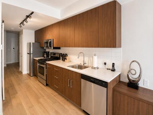 a large kitchen with wooden cabinets and a sink at Perfect Brand New Condo Downtown Sidney in Sidney