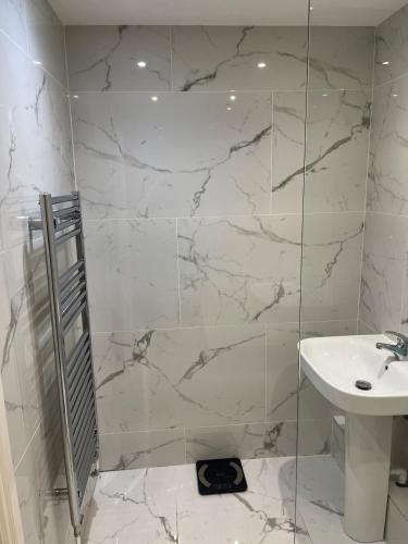 a white bathroom with a shower and a sink at Venue Apartment in Colne