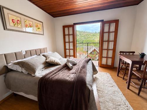 a bedroom with a bed and a table and a window at Pousada D' Paula in Campos do Jordão