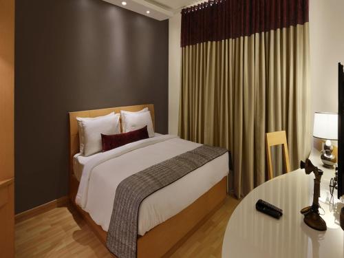 a bedroom with a large bed and a table at Melange Luxury Serviced Apartments in Bangalore