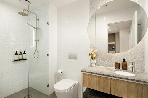 a bathroom with a toilet and a sink and a mirror at Stylish CBD Apartment with Courtyard and Parking in Newcastle