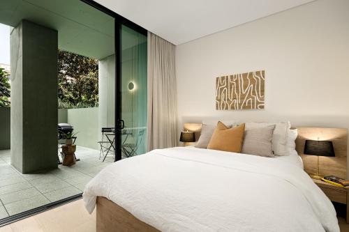 a bedroom with a large bed and a glass wall at Stylish CBD Apartment with Courtyard and Parking in Newcastle