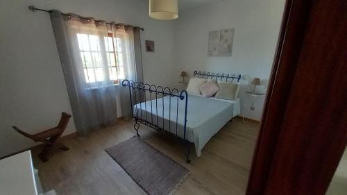 a small bedroom with a crib and a window at Monte da Cardela Nova in Melides