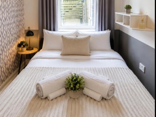 a large white bed with a vase of flowers on it at Easy Stay Jerviston in Mossend