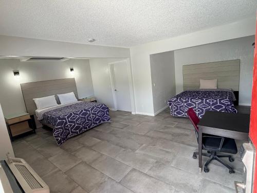 a hotel room with two beds and a desk at Rocky Inn Motel in Lynwood