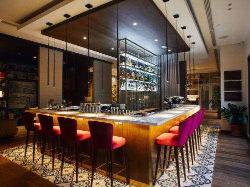 a bar in a restaurant with pink chairs at Manto Hotel Lima - MGallery Collection in Lima