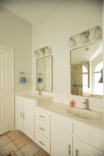 a white bathroom with two sinks and a mirror at Pet friendly Spacious 4 Bedroom home with large, fenced backyard, located to DFW airport, restaurants and shops in Irving