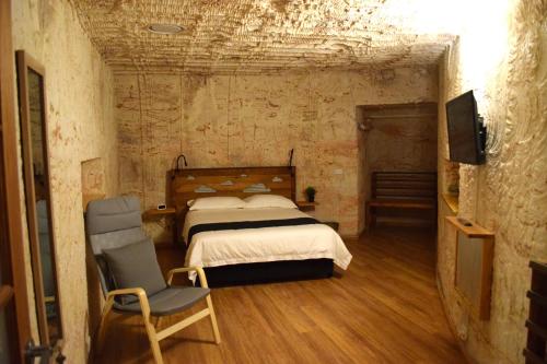 a bedroom with a bed and a chair in it at Dug Out B&B Apartments in Coober Pedy