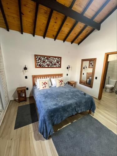 a bedroom with a large bed with a blue blanket at Chalé Vila do Aeroporto in Monte Verde