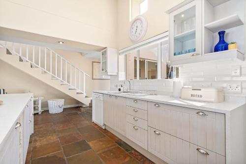 a kitchen with white cabinets and a staircase at Sea Haven 4 in Gordonʼs Bay