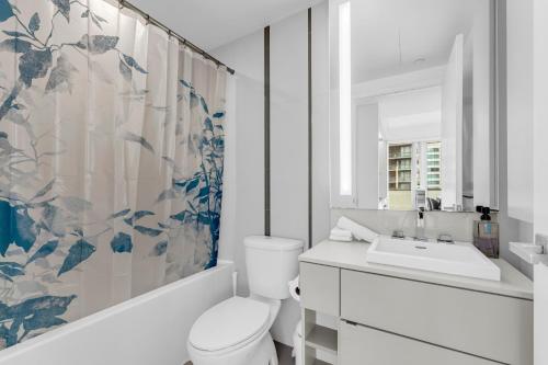 a bathroom with a toilet and a sink and a mirror at Altitude Residences in Toronto