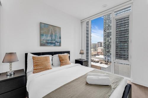 a bedroom with a large white bed and a large window at Altitude Residences in Toronto