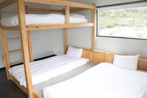 two bunk beds in a room with a window at ハーミットクラブ in Goto