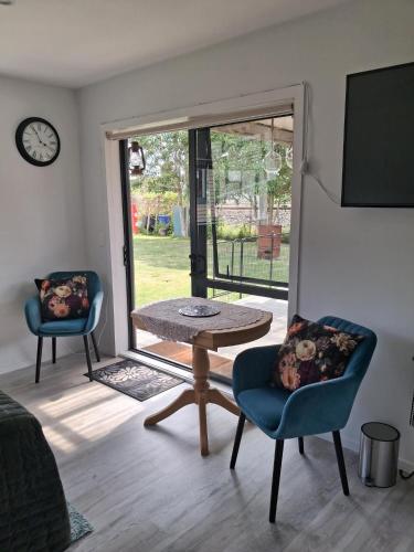 a living room with a table and chairs and a clock at Private Studio providing a comfortable space in Paraparaumu