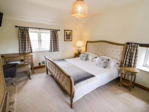 a bedroom with a bed and a desk and windows at Elmhurst Cottage in Quinton