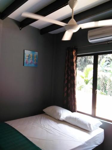a bedroom with a bed with a ceiling fan and a window at Green Peace Sungai Lembing in Sungai Lembing
