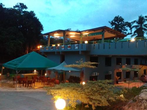 a building with tables and umbrellas at night at Green Peace Sungai Lembing in Sungai Lembing