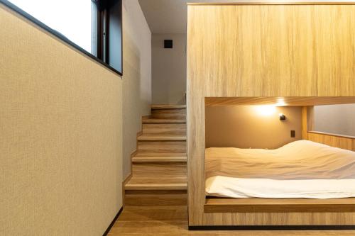 a small bedroom with a bed in a wooden wall at Forest Resort Walnut in Hakuba