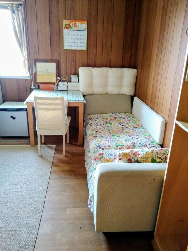 a small bedroom with a bed and a desk at Minshuku Zabaru in Ishigaki Island