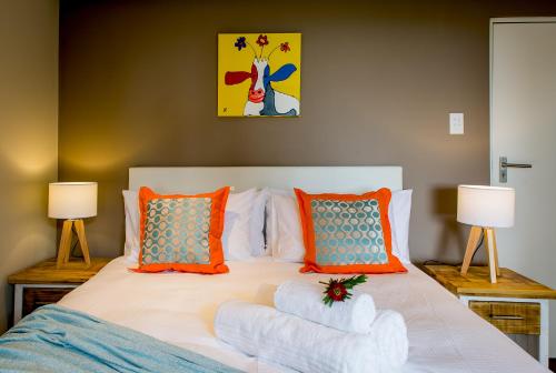 a bedroom with a bed with orange and blue pillows at Bloemenzee Boutique B&B in Gordonʼs Bay