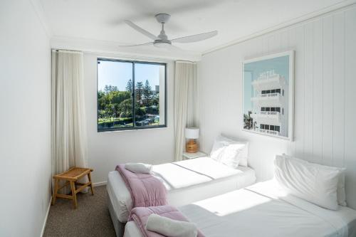 a white room with two beds and a window at Swell Resort Burleigh Heads in Gold Coast