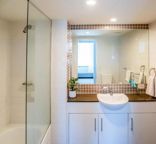 a bathroom with a sink and a shower and a mirror at Swell Resort Burleigh Heads in Gold Coast