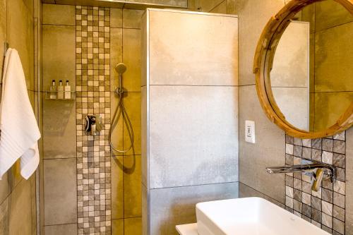 a bathroom with a shower with a sink and a mirror at Bloemenzee Boutique B&B in Gordonʼs Bay
