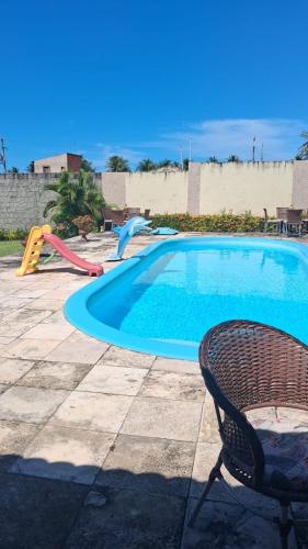 a pool with a slide and a chair next to it at Casa de praia Morro Branco in Beberibe