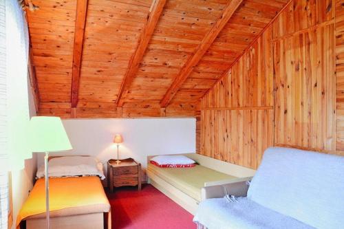 a bedroom with two beds in a room with wooden ceilings at Lakeside holiday villa, private garden in Wierzchowo