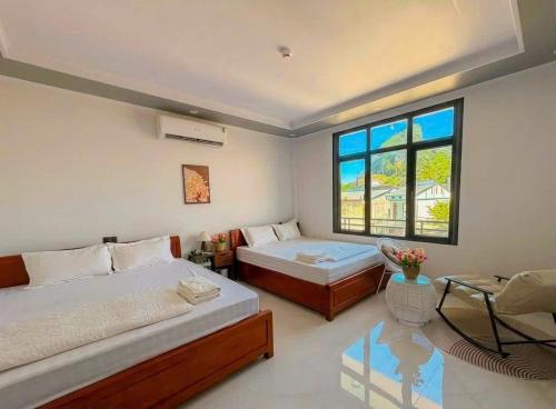 a bedroom with two beds and a window at Jade River Phong Nha in Phong Nha
