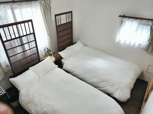 two beds in a room with white pillows at Tsukui 347 B in Yokosuka