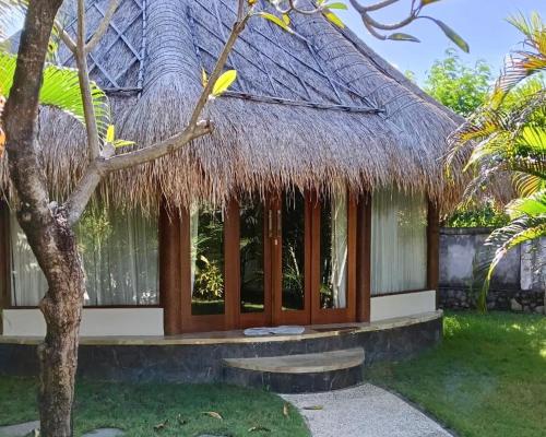 a thatch roofed house with a bench in front of it at Emocean Beach Boutique Dive Resort in Amed