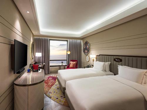 a hotel room with two beds and a window at Admiral Hotel Manila - MGallery Collection in Manila