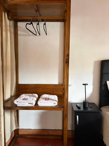 two towels on a shelf next to a bed at Zoola Suites Antigua in Antigua Guatemala