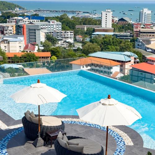 a swimming pool with two chairs and umbrellas at Samsara Hotel Pattaya in Pattaya South
