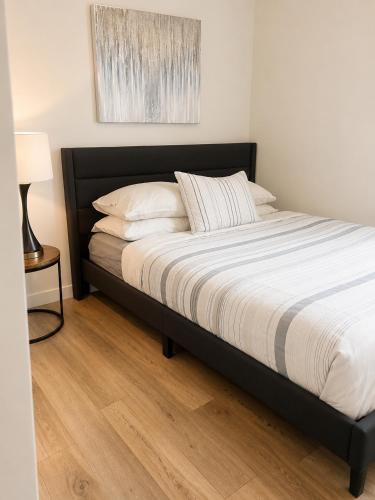 a bed with a black frame and white sheets and pillows at Lovely Brand New Suite in Sidney