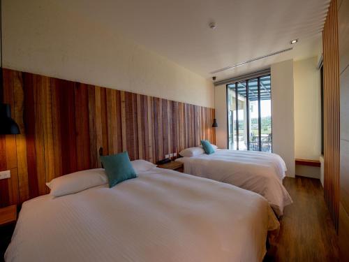 ein Hotelzimmer mit zwei Betten und einem Fenster in der Unterkunft Beras Manor Kenting in Altstadt von Hengchun