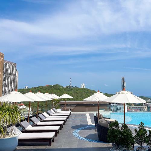 a row of lounge chairs and umbrellas next to a pool at Samsara Hotel Pattaya in Pattaya South