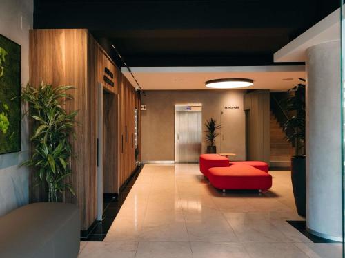 an office hallway with a red chair and a table at Ibis Styles Figueres Ronda in Figueres