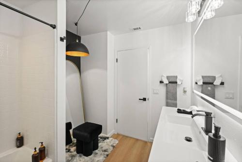 a white bathroom with a sink and a black stool at Heated Pool - Jacuzzi - Firepit - Game Room in Hemet
