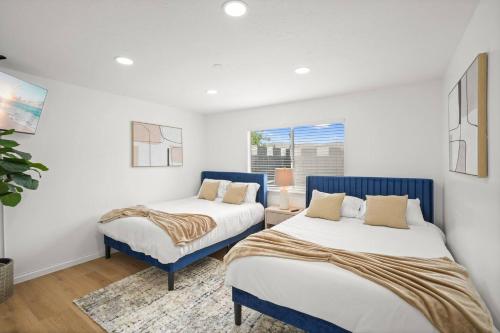 two beds in a room with white walls at Heated Pool - Jacuzzi - Firepit - Game Room in Hemet