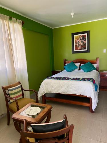 a bedroom with green walls and a bed and a table at RESORT ALAPA in Huancayo