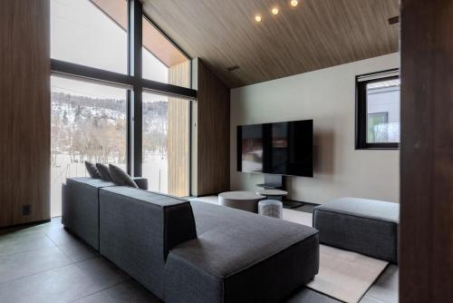 a living room with a couch and a flat screen tv at Forest Resort Oak in Hakuba
