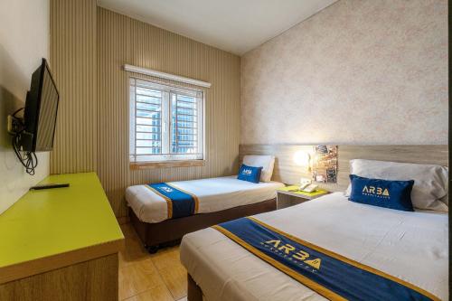 a hotel room with two beds and a television at Hotel Dahlia By ARBA in Jakarta