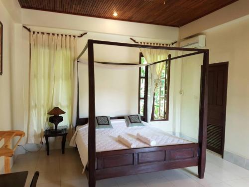 1 dormitorio con cama con dosel y ventana en Villa Thakhek en Thakhek